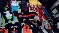 Image showing a variety of children's Halloween costumes and masks laid out on a surface