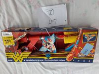 Front view of the boxed Wonder Woman Lollipop Folding Scooter showing the red and yellow colored scooter and box with tear damage.