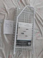 Folded white metal 4 tier shoe rack with packaging label showing assembled product with shoes on it.