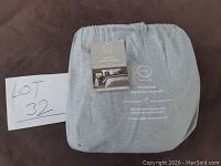 Folded gray flat sheet with attached product tag showing brand and fabric details.