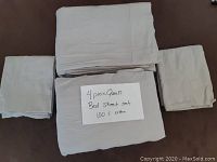 Folded 4 piece queen bed sheet set with handwritten note describing item and material.