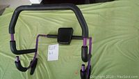 Top view of purple and black abs exercise machine showing ergonomic padded grips and central back support