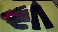 Photo showing the full set of girls winter jacket and snow pants laid flat on a surface.