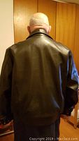 Back view of men's XL black leather jacket showing smooth leather material and ribbed waistband.