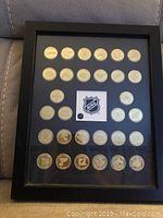 Front view of framed NHL team token set showing 31 round tokens including a center NHL shield emblem.