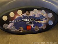 Full view of the 14 Canadian Millennium 2000 coins in the dark blue oval display with map background and red maple leaf emblem in center.