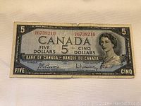 Front of 1954 Canadian five dollar bill showing Queen Elizabeth II bearing serial number 86738210.