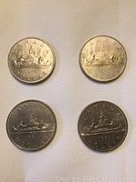 Reverse side of four Canadian one dollar coins showing voyageur canoe design and years 1976, 1979, 1980, 1981.