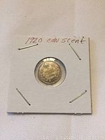 Front side of the 1920 Canadian 5 cent coin showing the crowned shield design in a cardboard holder.