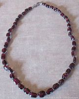 Full view of the garnet necklace laid flat showing shape and clasp.