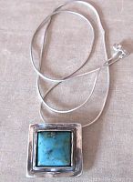 Full photo of silver chain and turquoise pendant laid flat showing overall necklace length and design