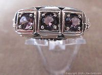 Close-up front view of the ring showing three round amethyst stones set in sterling silver square bezels.