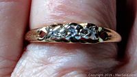 Front view of the yellow gold band showing three small round diamonds set in the center with decorative cutouts on either side of the stones.