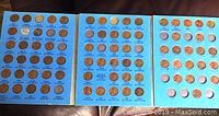 Collector book with Lincoln Head cents arranged in two open pages showing coins mounted in cut out slots with year and mint mark labels.