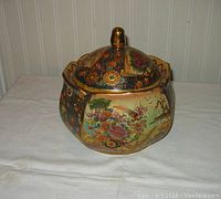 Front angle view showing the overall shape, painted decorations, and gold accented knob on lid