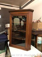 Full view of the mahogany shade wooden corner cabinet with glass front door.