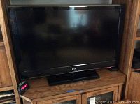 Front view of the LG 42 inch TV on a wooden entertainment stand showing the screen and base.