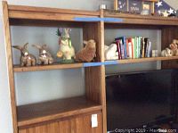 Wide shot of wooden shelves containing bunny figurines, books, and decorative items.