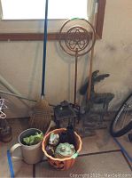 Photo showing pumpkin container with resin frogs, watering can, tin lantern, broom, brass spiral stake, and part of tin moose figures.