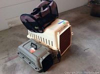 Three pet crates stacked in garage showing overall condition and size comparison