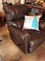 Right side view showing padded armrest and leather texture, along with the included pillow on the seat.