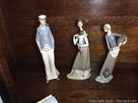 Three porcelain Lladro figurines on display showing full front view of each figure.