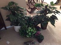 Faux floral plants grouped together, showing various sizes and leaf types along with baskets used for some plants.