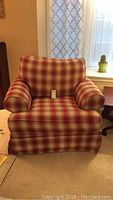 Front view of Broyhill armchair with red and beige plaid fabric upholstery, padded arms and skirted base.