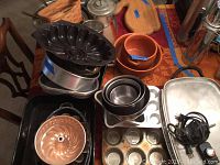 Overview showing muffin tins, bundt cake pan, roasting pan, and some bowls with griddle cord on table.