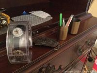 Lot displayed on wooden dresser showing all three items: the Mickey Mouse watch in a clear plastic case, the Stanley 1993 belt buckle, and the travel razor with metal case.