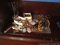 Photo of assorted costume jewelry including necklaces, bracelets, and earrings in a box on a shelf.