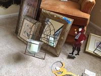 Photo showing two wall sconce candle holders with metal frame and glass holders, a framed decorative mirror, and Cirque Du Soleil metal figurines including one red jacket figure and one yellow figure.