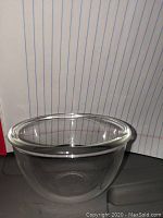 Clear glass bowl with smooth rim photographed against lined paper backdrop to show size and clarity.