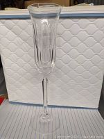 Single Mikasa crystal champagne flute glass with vertical cut pattern on bowl and hexagonal base on white background.