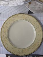 Close up of a large Noritake bone fine china plate with cream-beige floral border and gold edge
