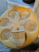 Set of 12 tea cups in protective foam sleeve with one cup displayed outside the foam.