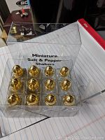 Set of 12 miniature gold tone salt and pepper shakers in clear plastic box labeled 'Miniature Salt & Pepper Shakers'