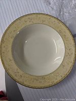 Close-up front view of a Noritake bone china soup bowl showing beige floral border and gold rim.