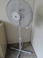 White metal floor fan shown from the front with mesh grill and three blades visible.