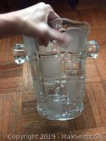 Crystal ice bucket held by hand, showing the frosted and clear geometric square patterns and handle detail.