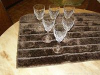 Six crystal wine glasses arranged on a dark brown textured cloth to show overall quantity and condition.