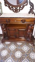 Full view of the solid wood entrance hall table showing drawer, lion figure supports, cabinet doors, and lace runner on top.