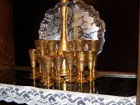 Front view of vintage Italian decanter set comprising gold-tone decanter and matching goblets on silver scalloped tray