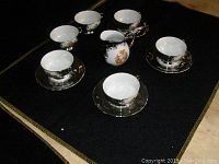 Overall set with 6 cups, 4 saucers, and creamer arranged on black fabric.