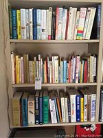 Full view of three shelves filled with various books including fiction and medical titles.