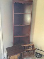 Tall triangular wooden corner cabinet with open shelving against a wall