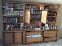 Full view of six piece Mid Century Modern wall unit with contents including glassware and decorative items