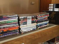 Stack of various DVD titles arranged horizontally on a surface, showing multiple movie and show titles in standard DVD cases.
