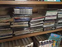 Large stacks of music CDs in jewel cases displayed on shelves. Visible titles include 'The War Years' series discs and other collections.