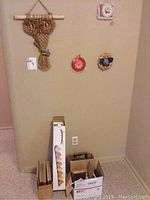 Macrame owl wall hanging and three small decorative hanging pieces on a wall above several boxes containing picture frames and candle stand